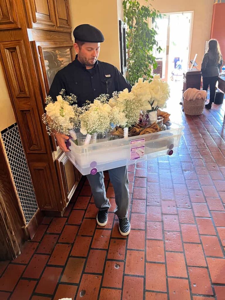 Man carrying white wedding rose arrangements