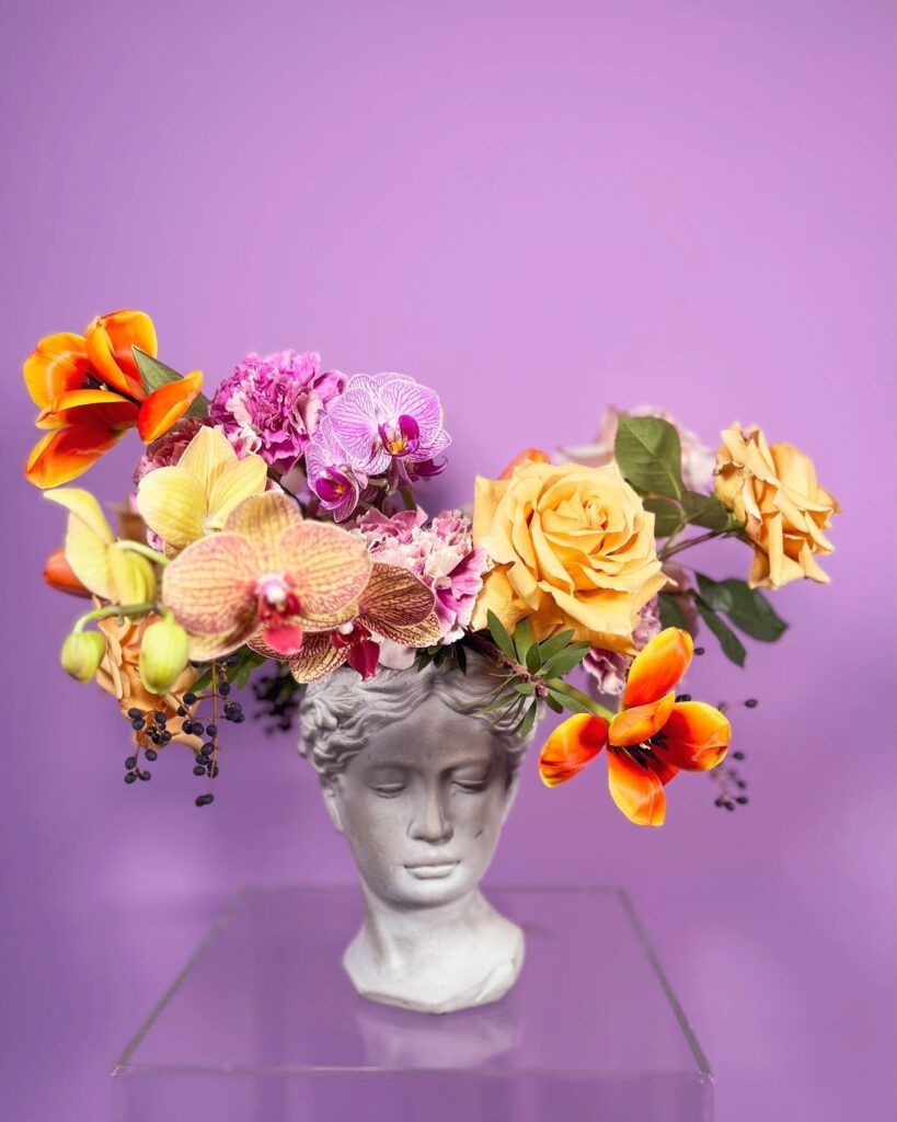 Flower arrangement with orchids, roses, tulips in a vase in the shape of Greek goddess Athena